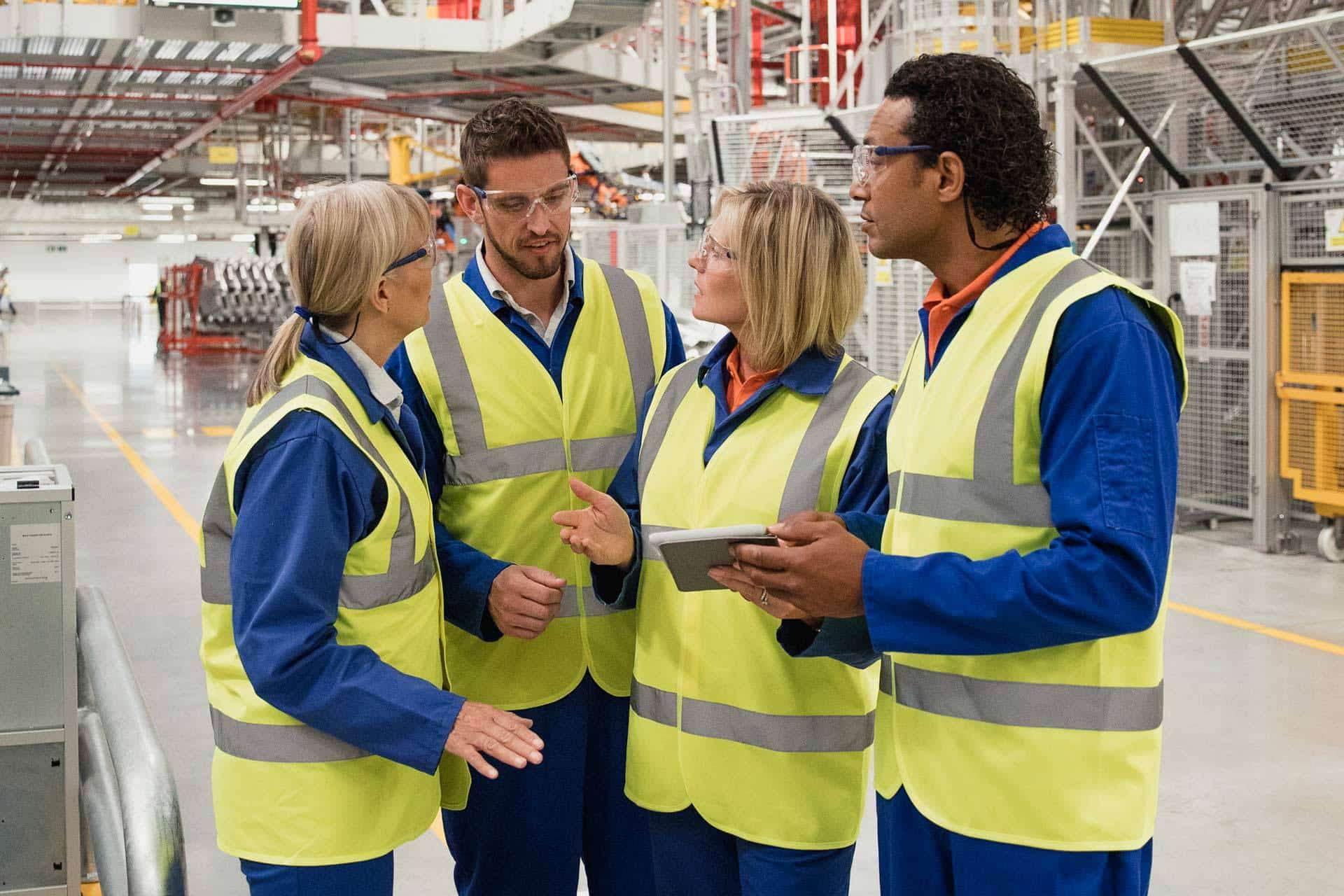 Workers in safety vests discussing inside an industrial facility.