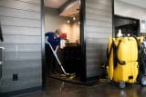 Person cleaning office hallway floor with equipment and mop.