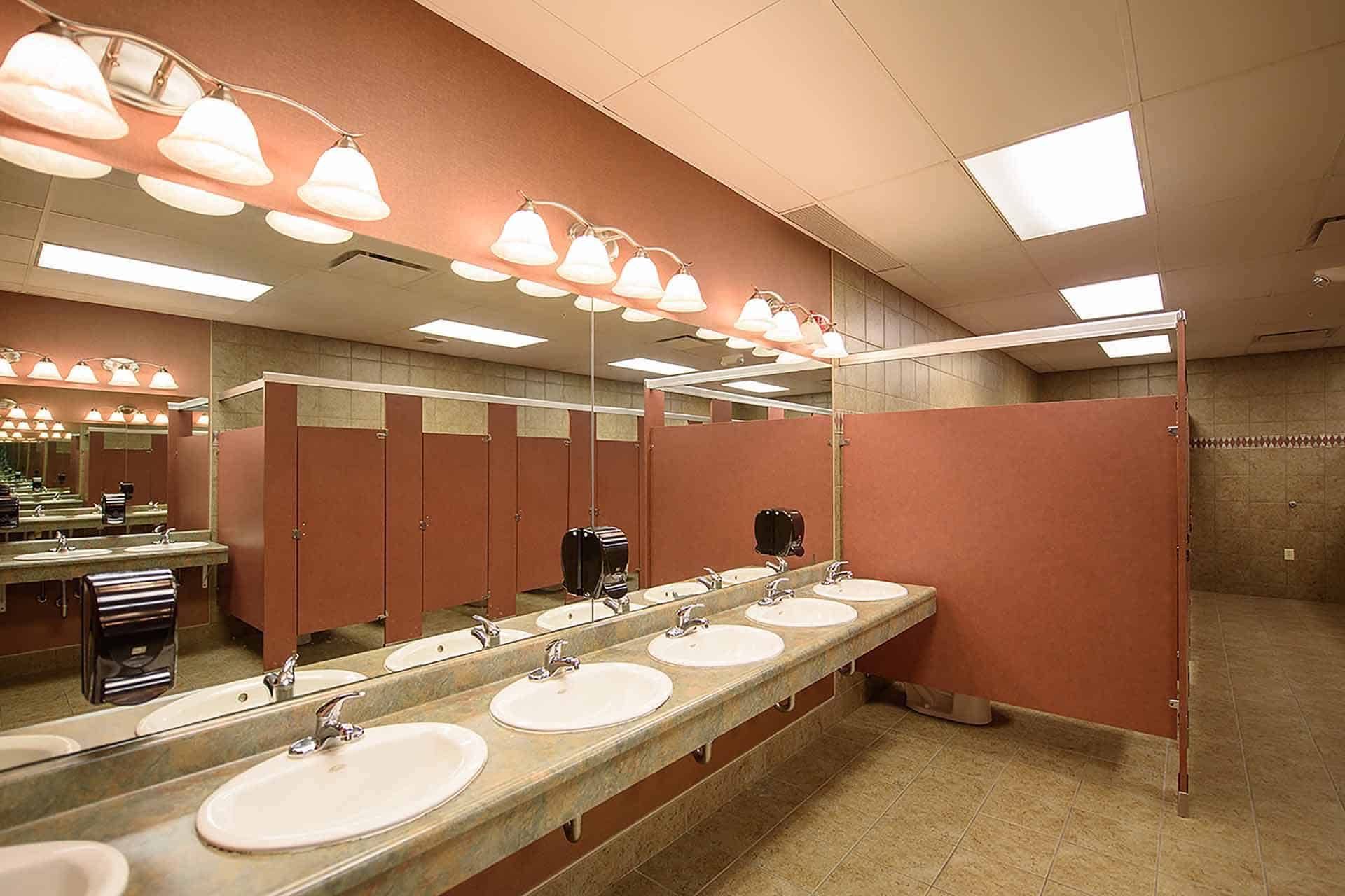 Public restroom with sinks, mirrors, and red stall dividers.