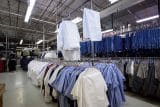 Racks of blue and white uniforms in an industrial warehouse.