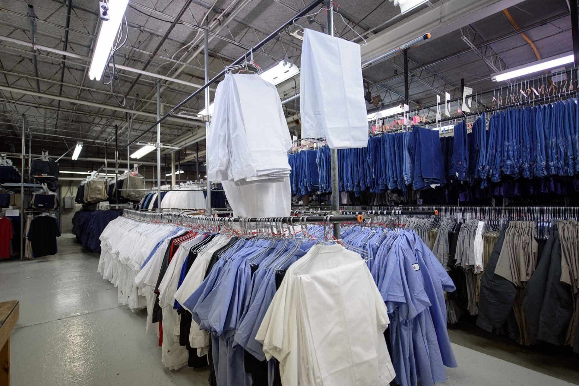 Racks of blue and white uniforms in an industrial warehouse.