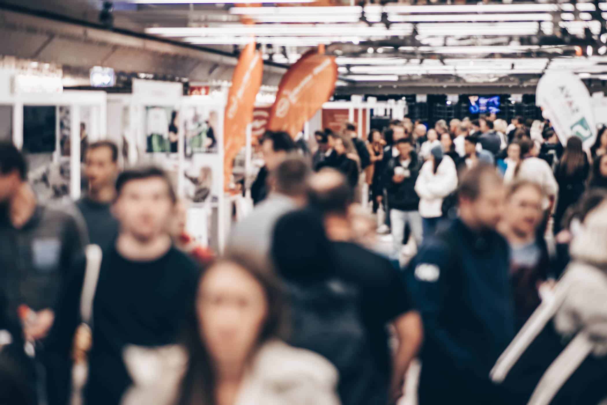A crowded indoor event with promotional giveaways and people near booths.