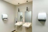 Two sinks with mirrors and wall-mounted paper towel dispensers in a restroom.