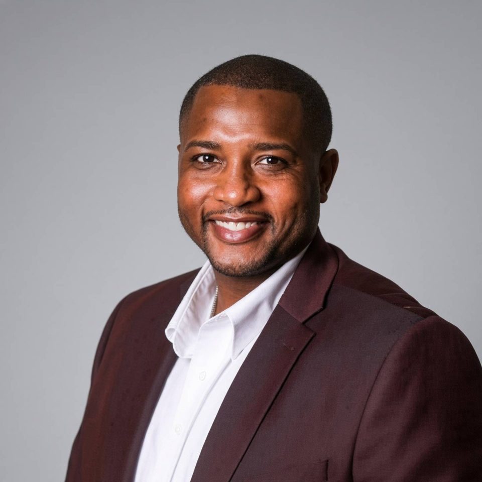 A smiling man in a dark blazer and white shirt.